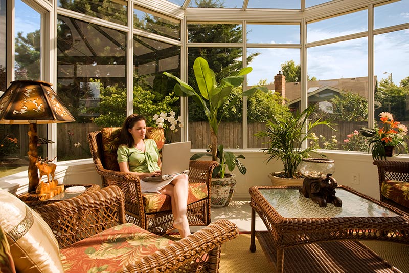 Woman sitting in a chair, Fall decorated Sunroom, Global Solariums